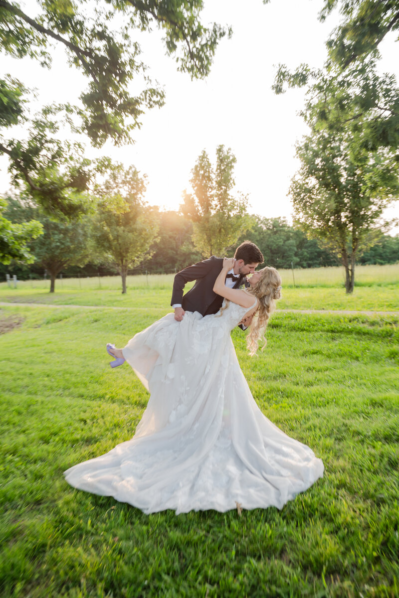 Bride and groom dip kissing halfway down the isle with their family and friends smiling on them