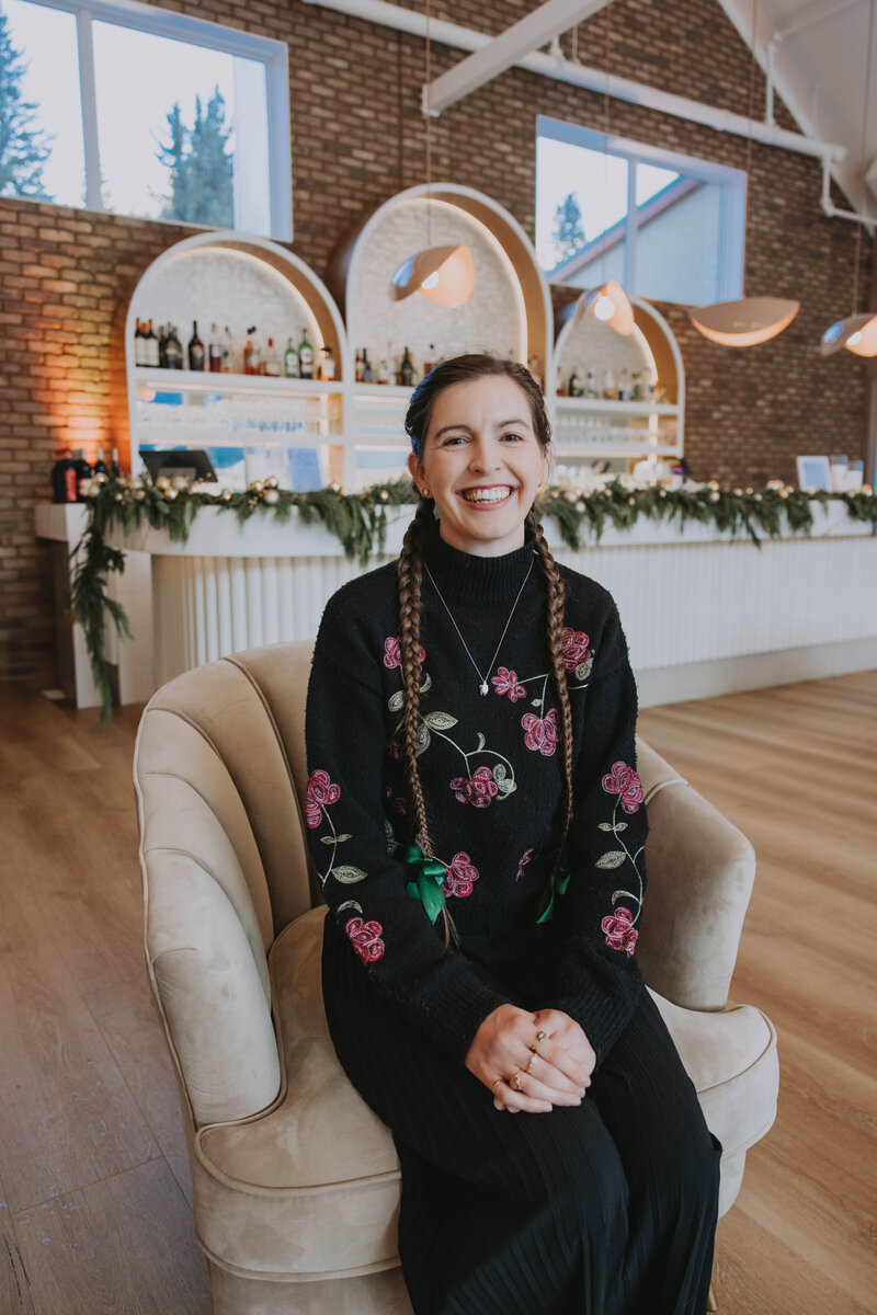 Event planner in cozy winter outfit and grey beanie smiling in snowy Banff forest – Rocky Mountain Wedding Collective