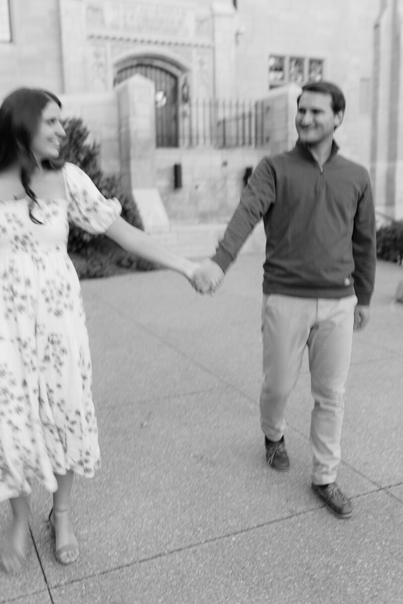 Blurry candid moment of a couple holding hands and smiling towards each other.