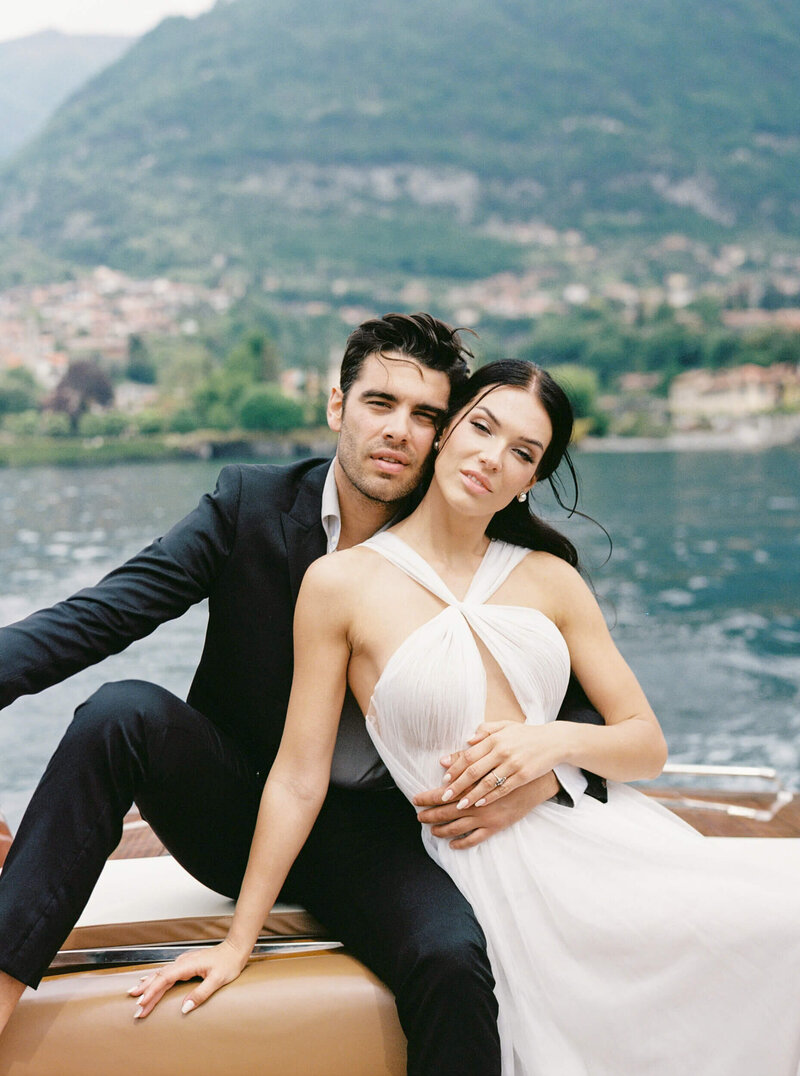 Candid wedding photo of a couple on a boat sitting beside each other on Lake Como in Italy