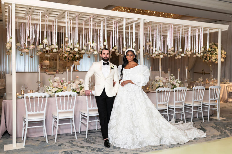 Bride and groom pose for portrait at wedding reception filled with lush white floral installations