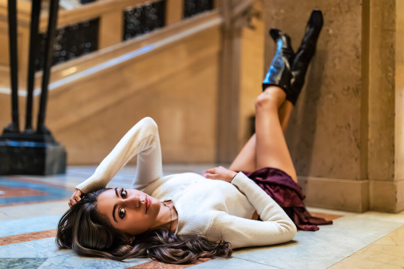 a female graduating senior lays on the Pittsburgh Museum floor for this creative portrait.
