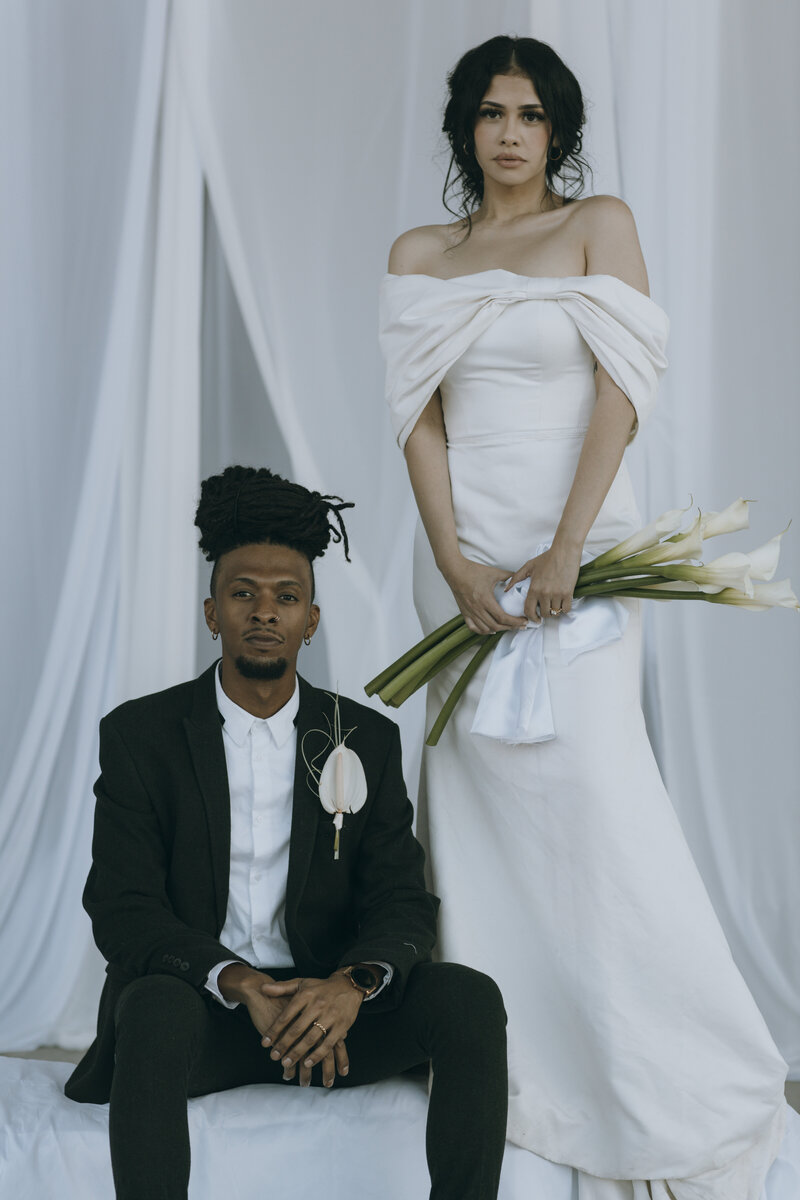 Editorial minimal photography of bride and groom with long lilies and easy and relaxed posing