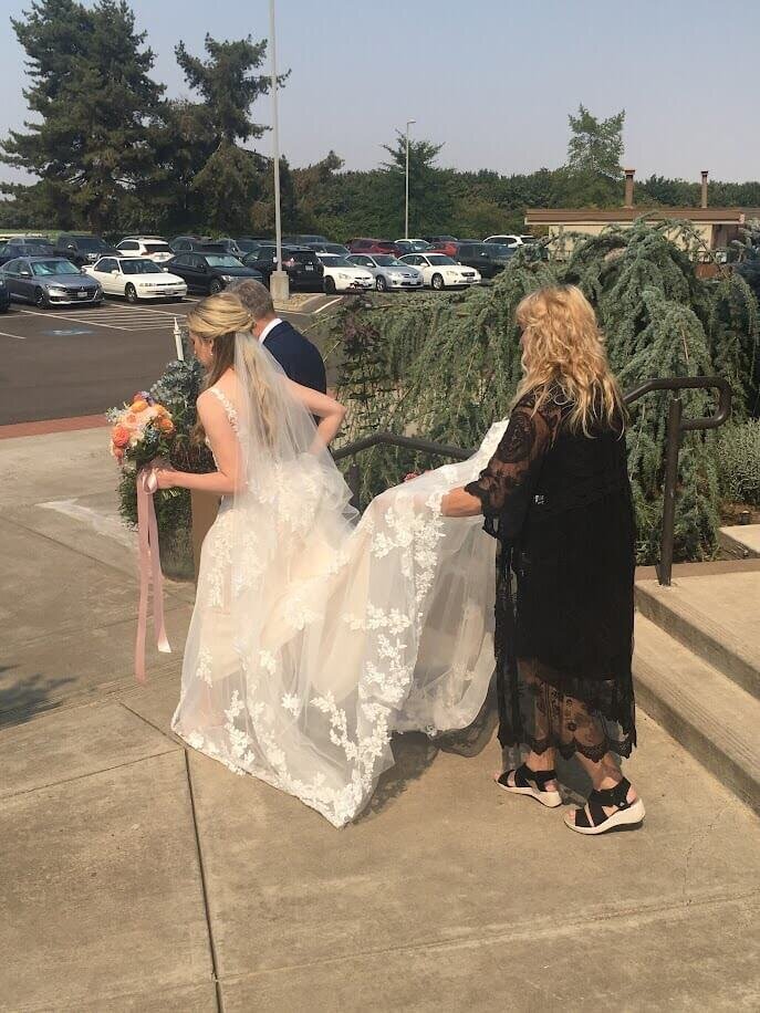 DelJean, a florist in Eugene, Oregon, helps a bride by carrying her train.