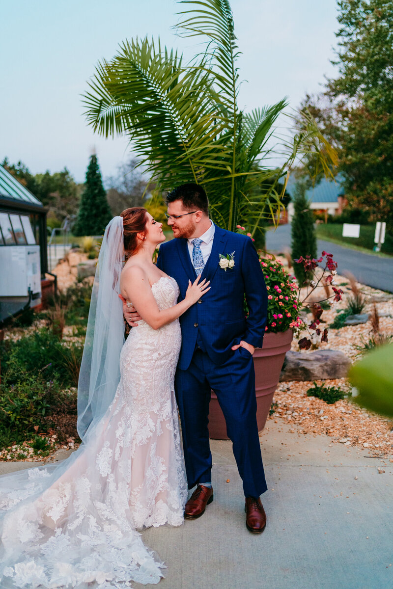 Bride and groom smiling at each other after their ceremony near a palm tree at a cozy outdoor wedding venue.