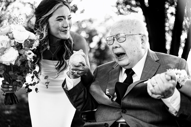 A bride with a tear rolling down her face holding her blind grandfathers hand after the ceremony. Lots of emotion from both people and this photo won a Fearless Award