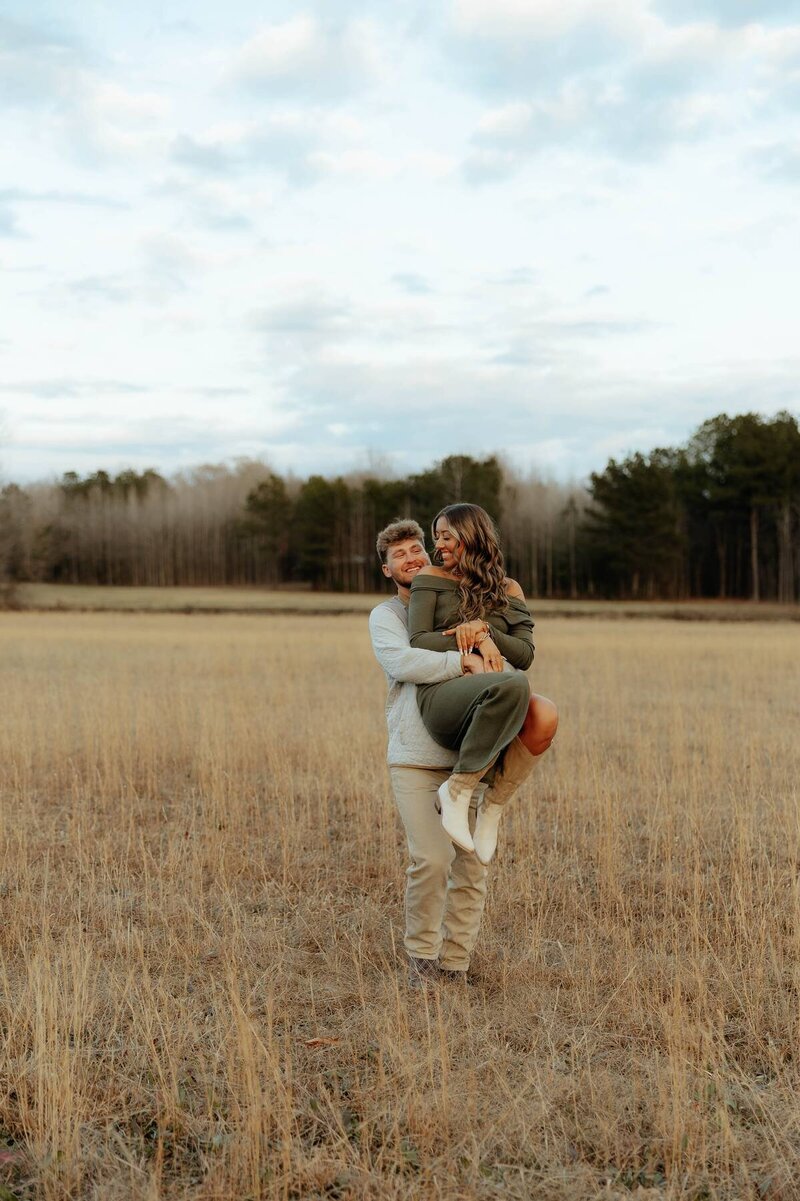 fun couples session with man lifting woman up hugging her