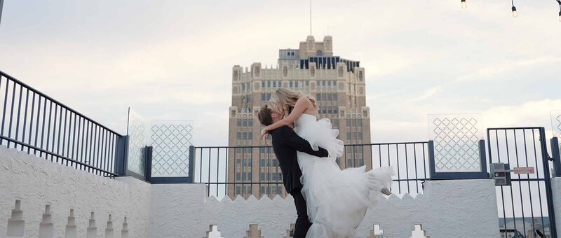 Groom lifting the bride and kissing on a rooftop in dallas.