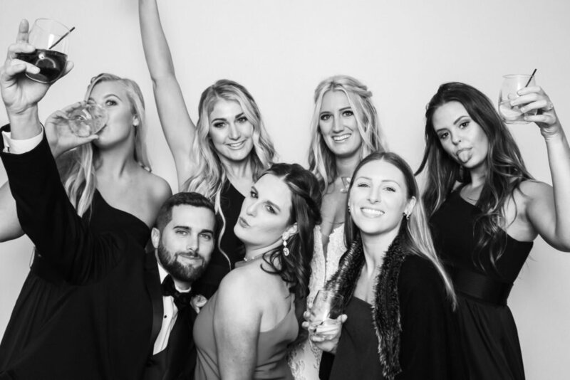 group of friends posing with drinks and smiles in the black and white glam printed photo booth