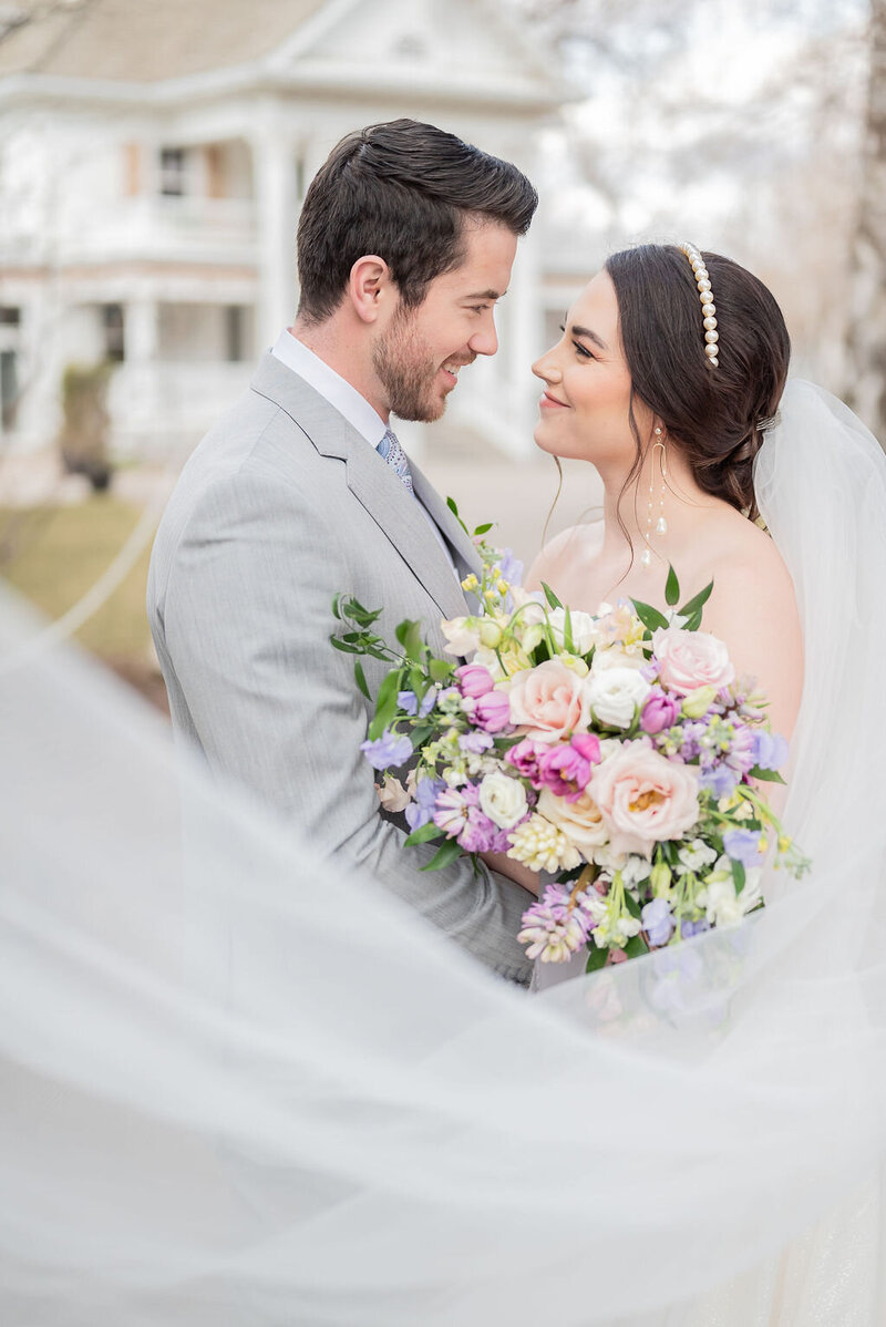 A veil shot of bride and groom at Norland Estate with lavender and pink bouquet.