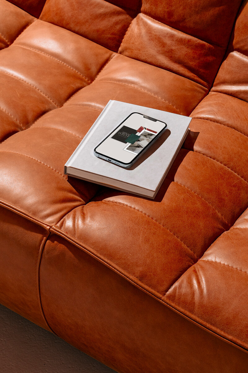 Phone displaying moodboard of Spa brand identity that is on a book on a leather couch