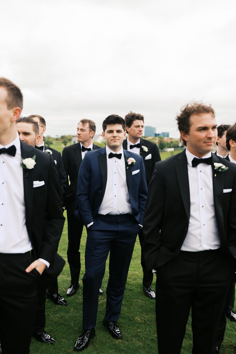 Groom surrounded by his groomsmen in classic suits at Dallas wedding venue. 