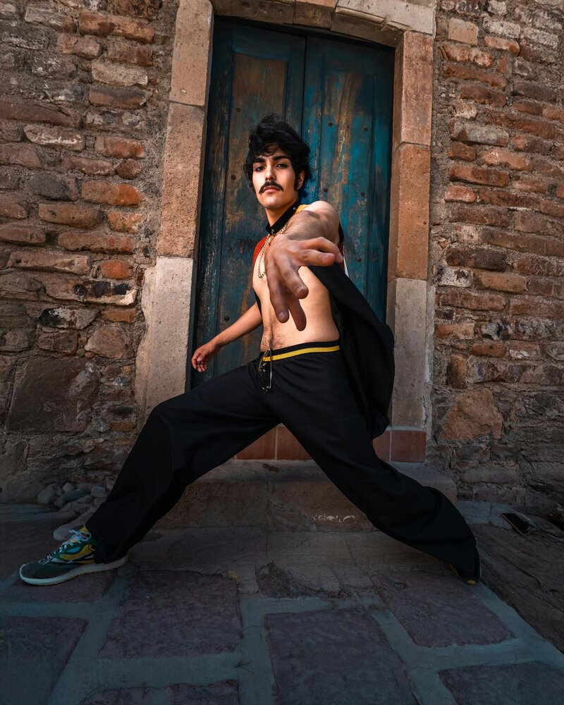 Young man dancing with arm stretched out toward camera