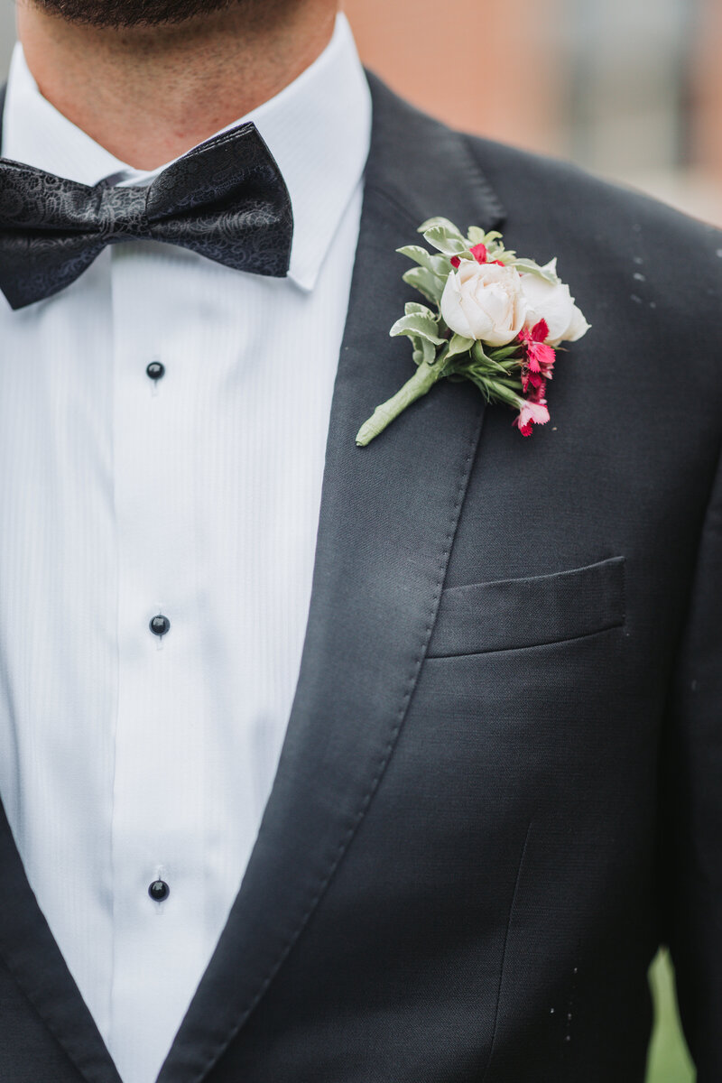 Close up detail shot of the Groom's boutonnière and suit jacket