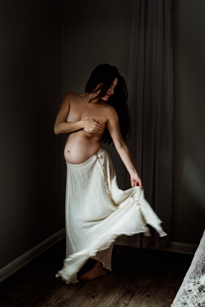 Topless pregnant woman fanning skirt