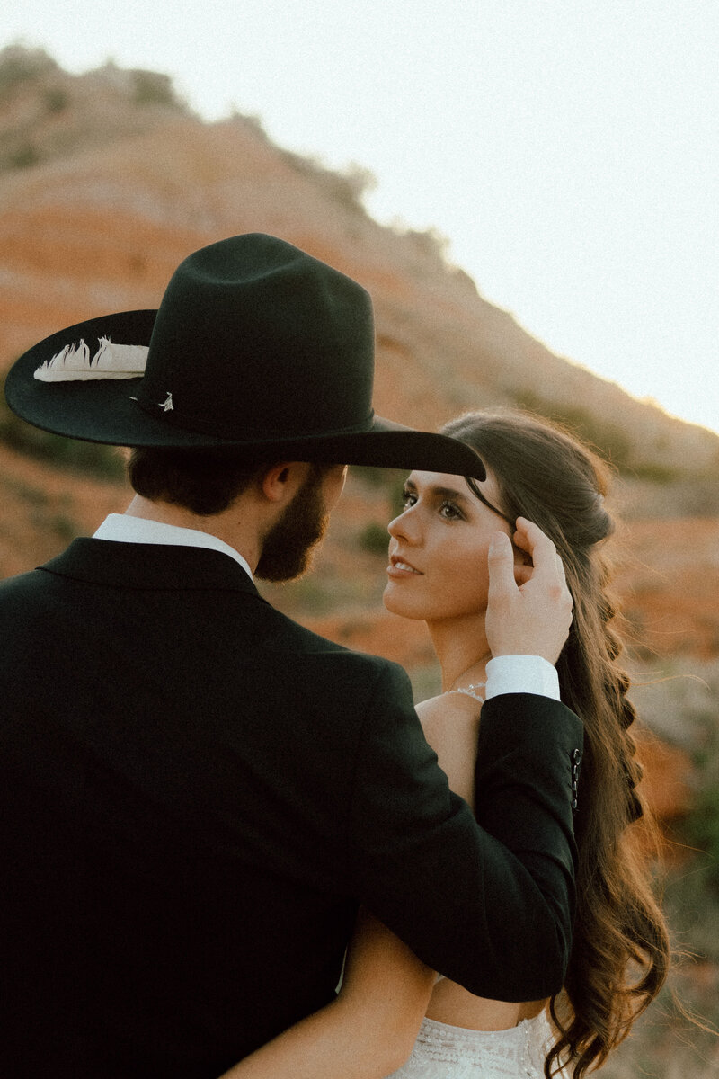 groom brushing brides hair away taken by oklahoma wedding photographer