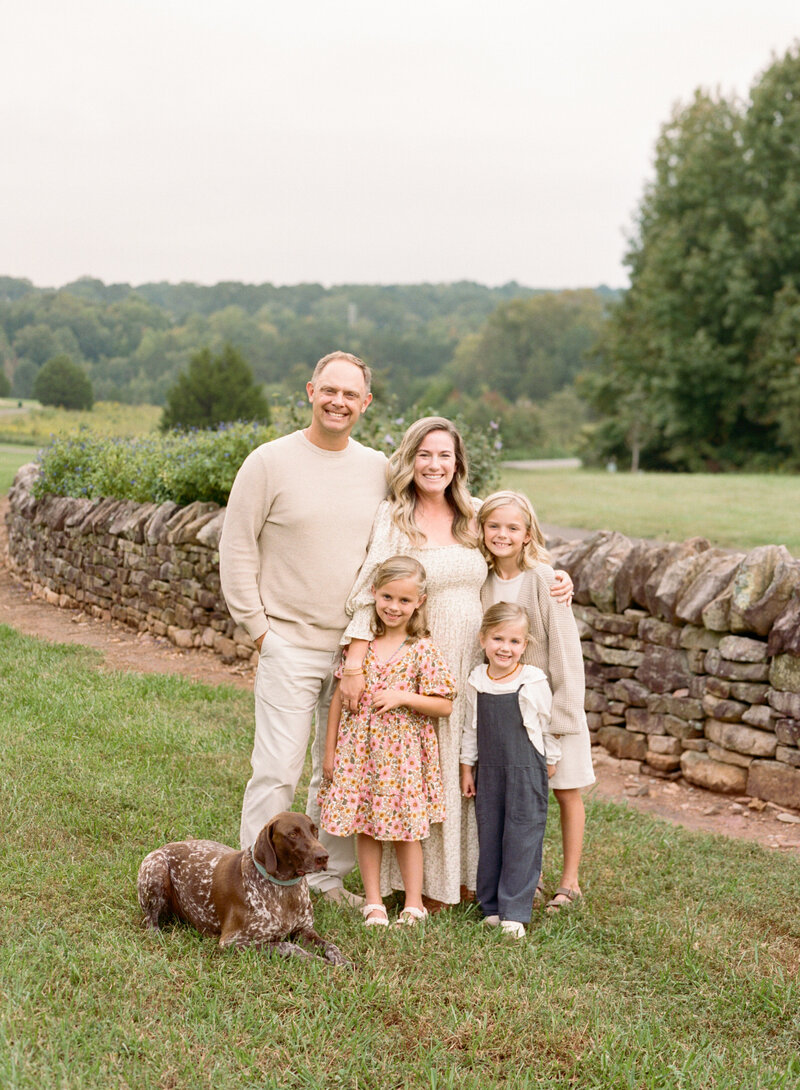 Image of family smiling at the camera with a german shorthaired pointer dog. Raleigh Newborn Photographer
