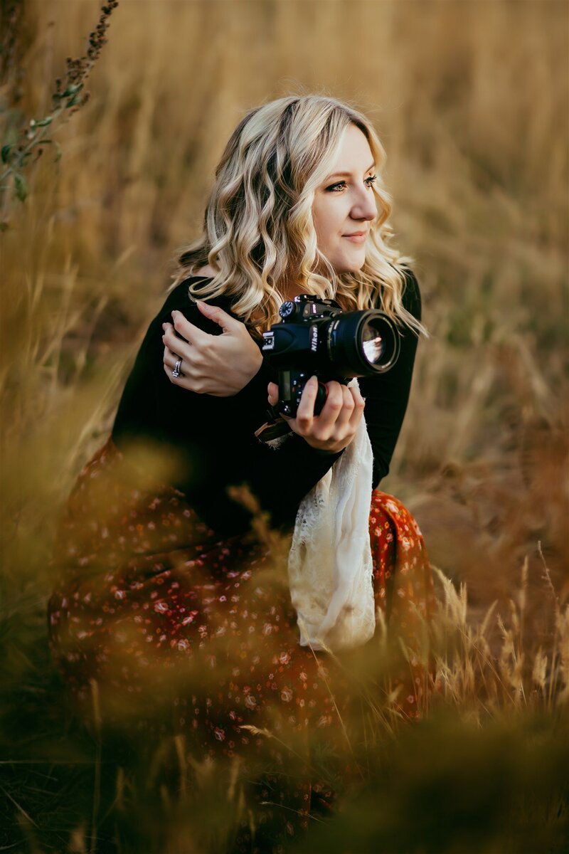 Photographer holding a camera, looking away into the sunset in Westsyde, Kamloops. 