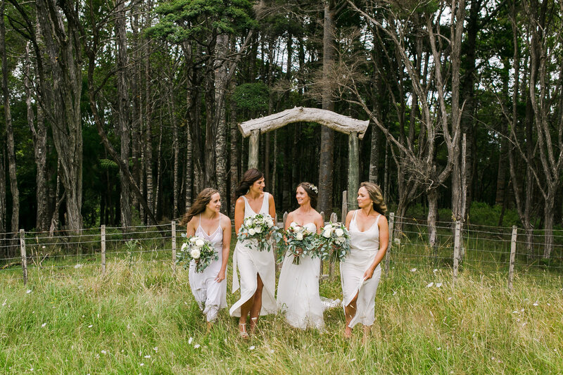 Bridesmaids in long grass in front of arch