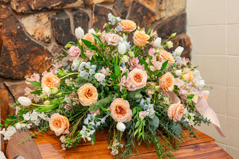 peach roses white tulips pink lizzyathus blue delphinium casket spray funeral flowers