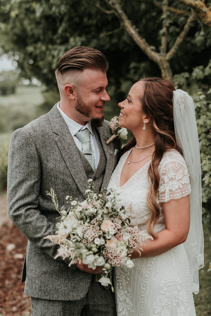 Smiling bride and Groom holding spring bridal bouquet at Bury Court Barn, Farnham