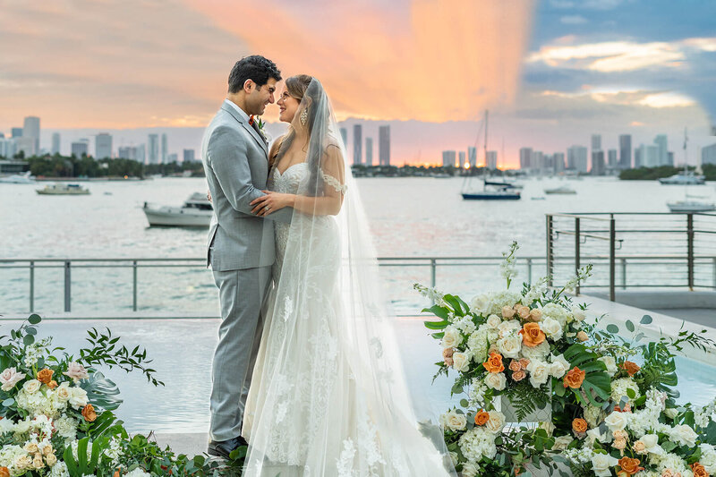 Bride and groom standing together at sunset with the Miami skyline behind them at the Mondrian South Beach, photographed during the golden hour portion of their First Look wedding photo timeline.