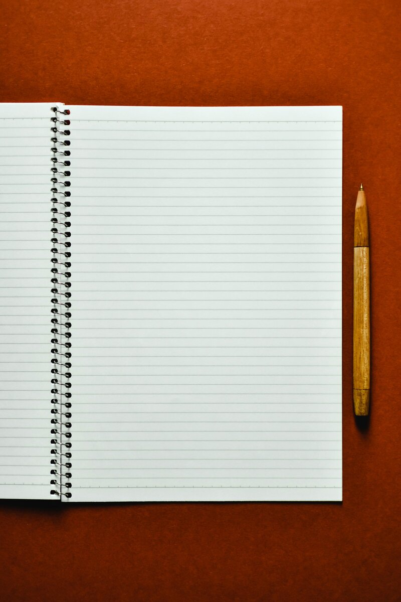Open lined notebook with wooden pen on orange background for career coaching notes and reflection