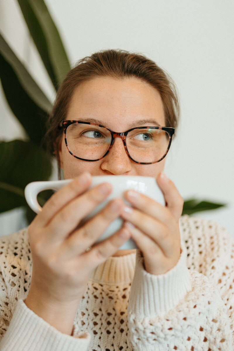 Two coffee cups filled with coffee on a white brick, centered around SEO FAQs for working with The Comma Mama Co.