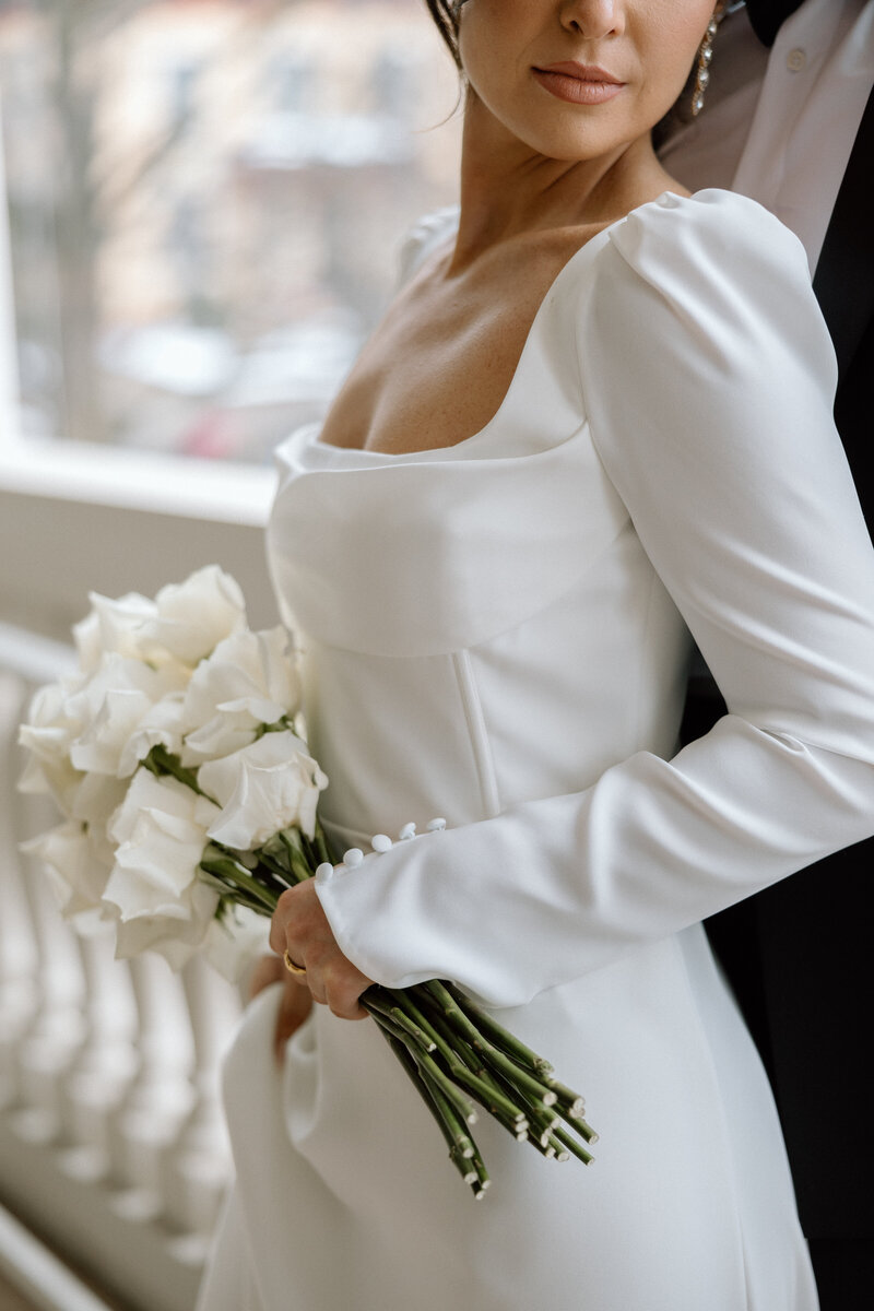 Bride holding bouquet of white roses on balcony.  at the. Westmoreland Club