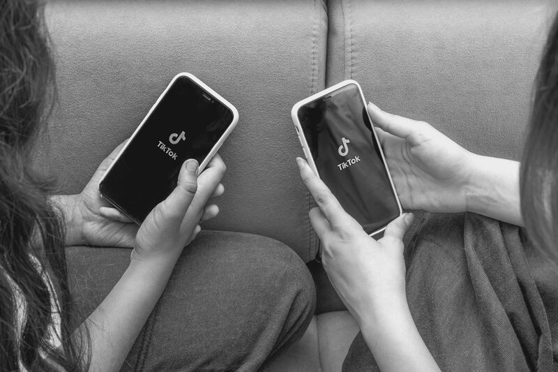 Two people opening the tiktok app on their phones.