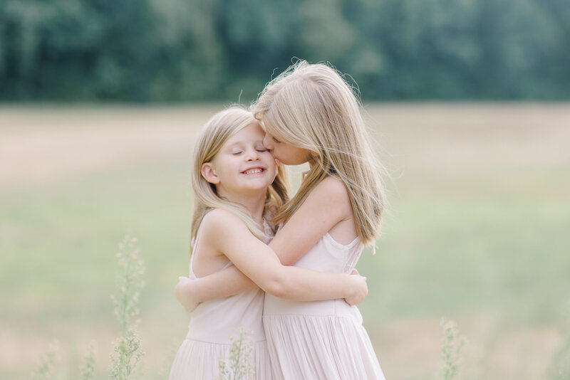 Sisters hugging each other in a field