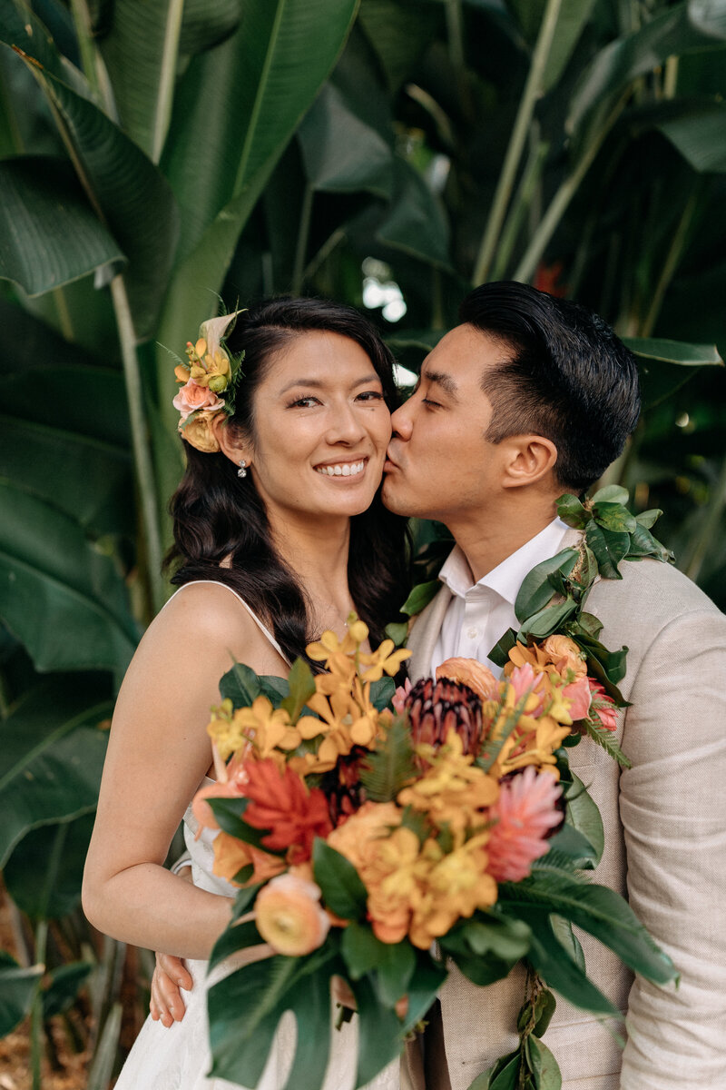 Bride and groom at Holualoa Inn in Hawaii, celebrating their wedding with a vibrant tropical bouquet. A stunning moment from their luxury destination wedding.
