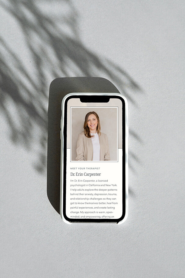 A mobile phone displaying a photo of Dr. Erin Carpenter smiling at the camera.