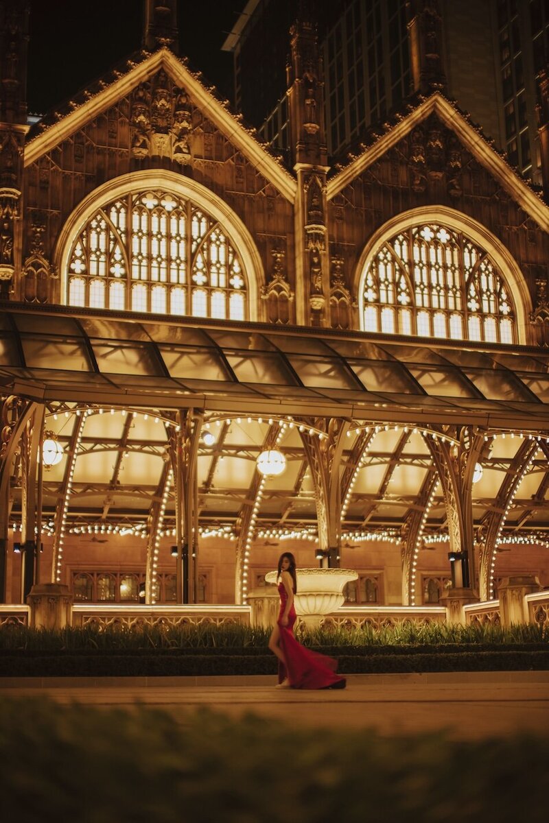 Destination couture photoshoot with a woman in. a red gown at night in the city.