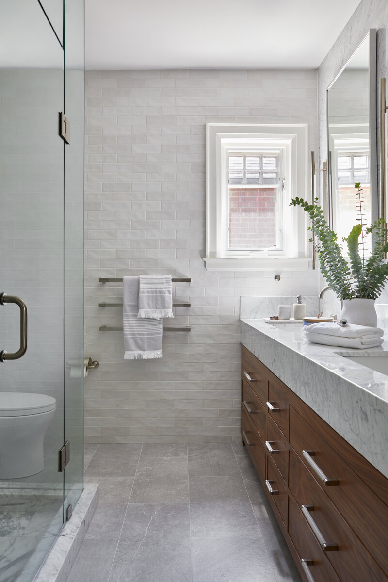 Before and after transformation of an outdated bathroom into a bright, modern bathroom with a custom walnut vanity, textured zellige wall tiles, and marble countertop and shower accents