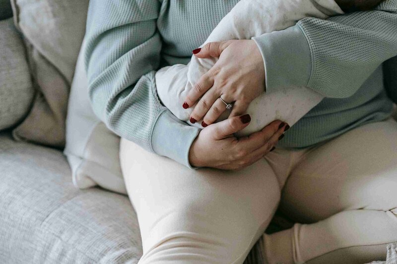 A woman lovingly holds her baby on a couch, representing perinatal support in Evanston, Illinois.