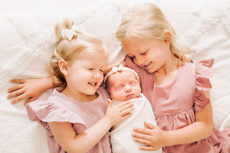 Springfield MO newborn photographer Jessica Kennedy of The XO Photography captures sisters cuddling newborn baby girl