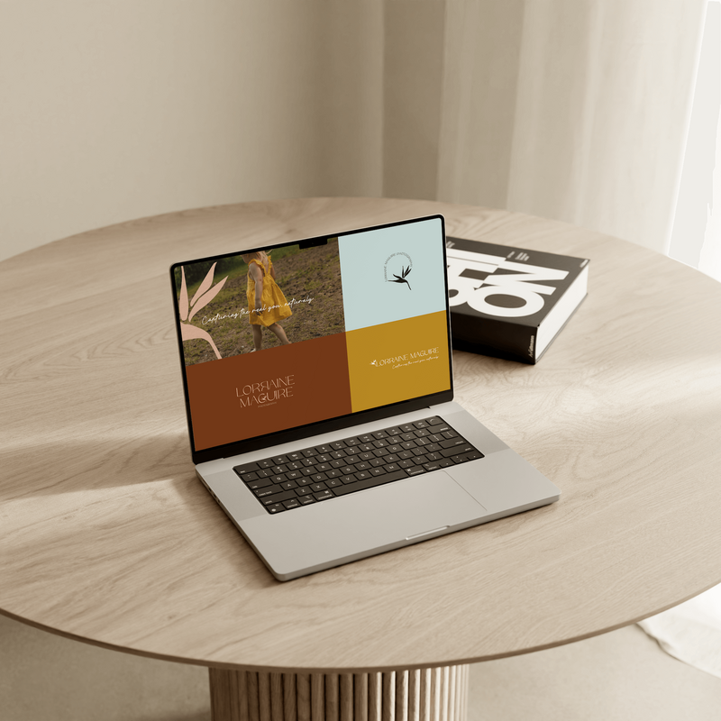Branding for Lorraine Maguire Photography on an open laptop on a round table with a book behind it