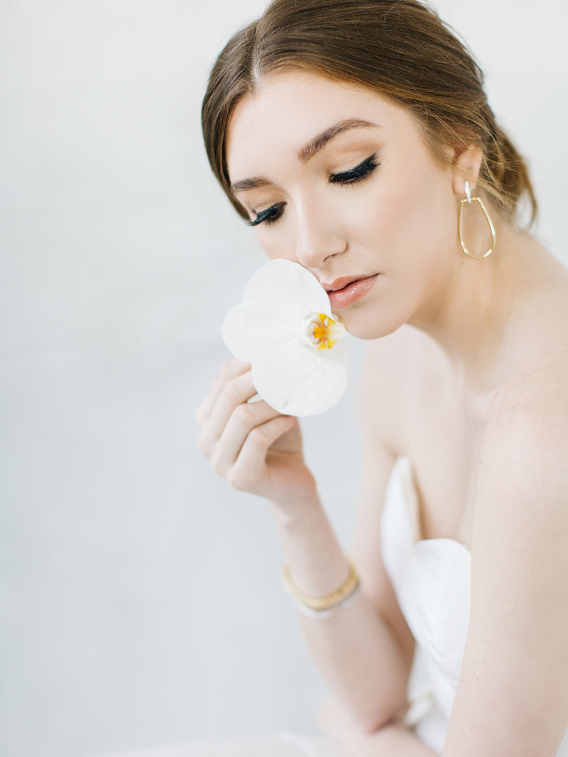 bride wearing pant suit with cape wedding dress holding an all white orchid bouquet