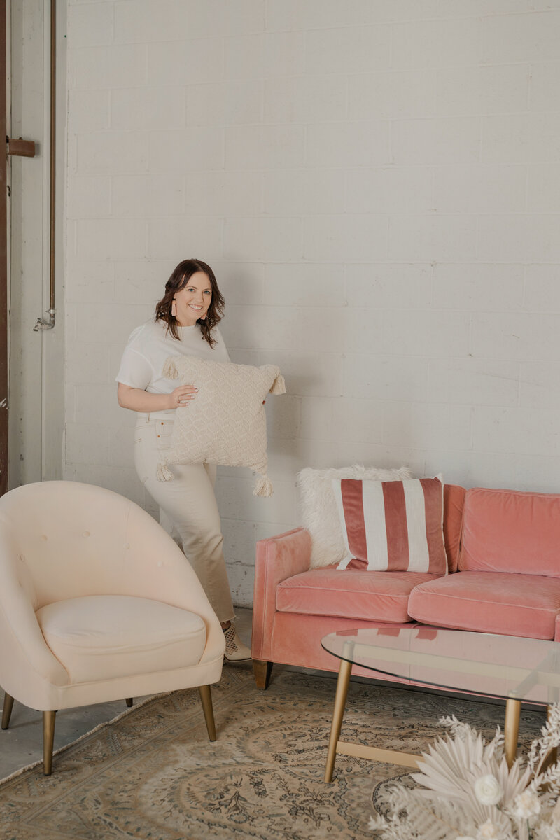 woman arranging pillows on a pink velvet couch