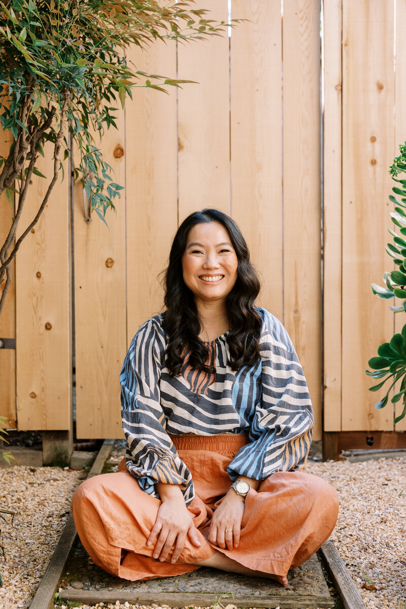 Joanne Lai a somatic therapist in Fresno sitting and smiling