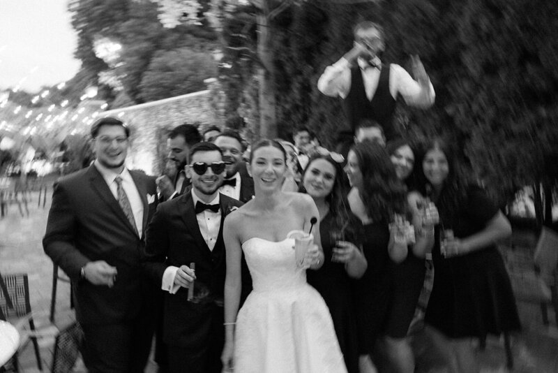 Bridal party celebrate with newlyweds in black and white blur on Long Island, NY.