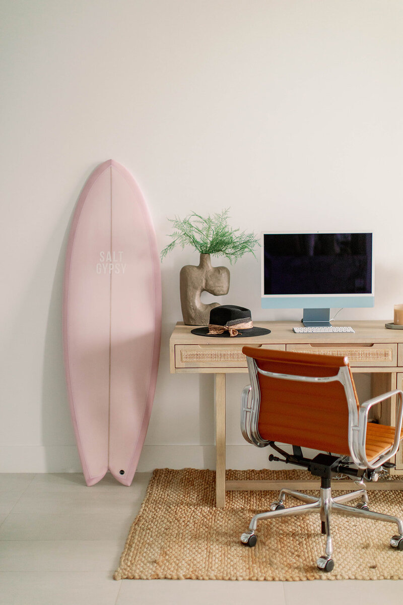 Wooden desk with leather chair and pink surf board