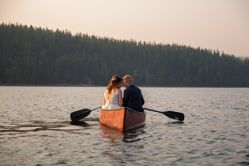 A bride and groom sit in a canoe together on a lake after their elopement ceremony in Glacier National Park.