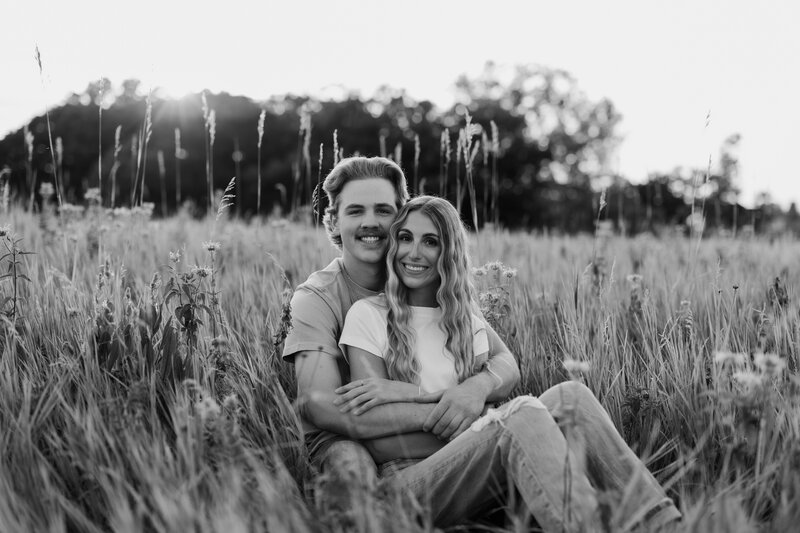 woman and man smiling at camera sitting in field