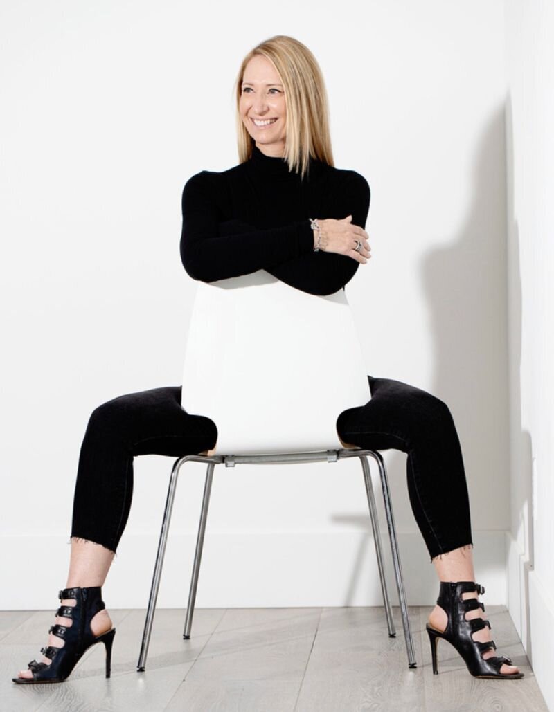 The CEG Agency founder posing with a chair in business attire. 