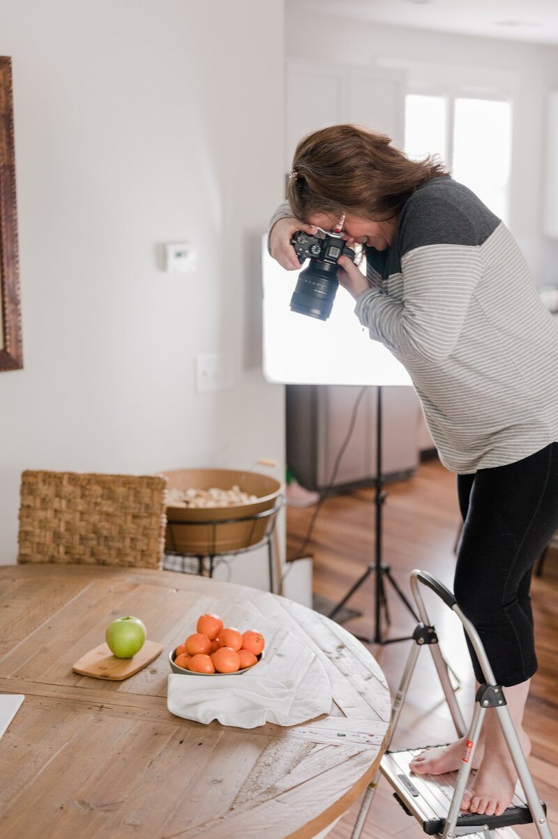 Image of Amanda, lead brand photographer, at work photographing food displays on a kitchen table