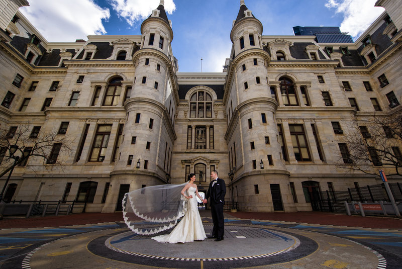 Bride and groom posing in the middle of City Hall in Philadelphia, blending urban elegance with their elopement celebration.