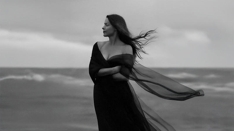 black and white image with lady looking into the distance with flowy fabric off her shoulder