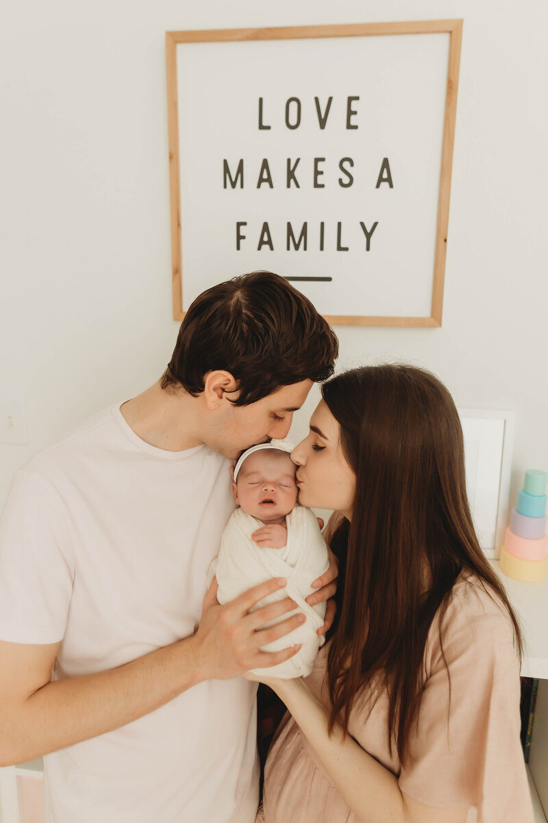 Parents with their newborn baby in a white nursery